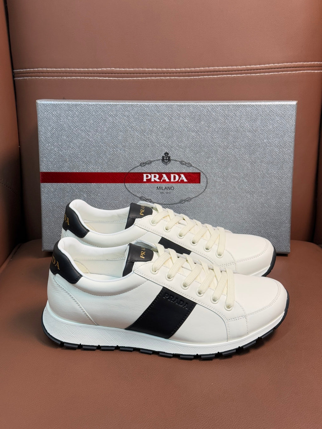 White Prada unisex low-top sneakers with black stripe detail and lace-up front