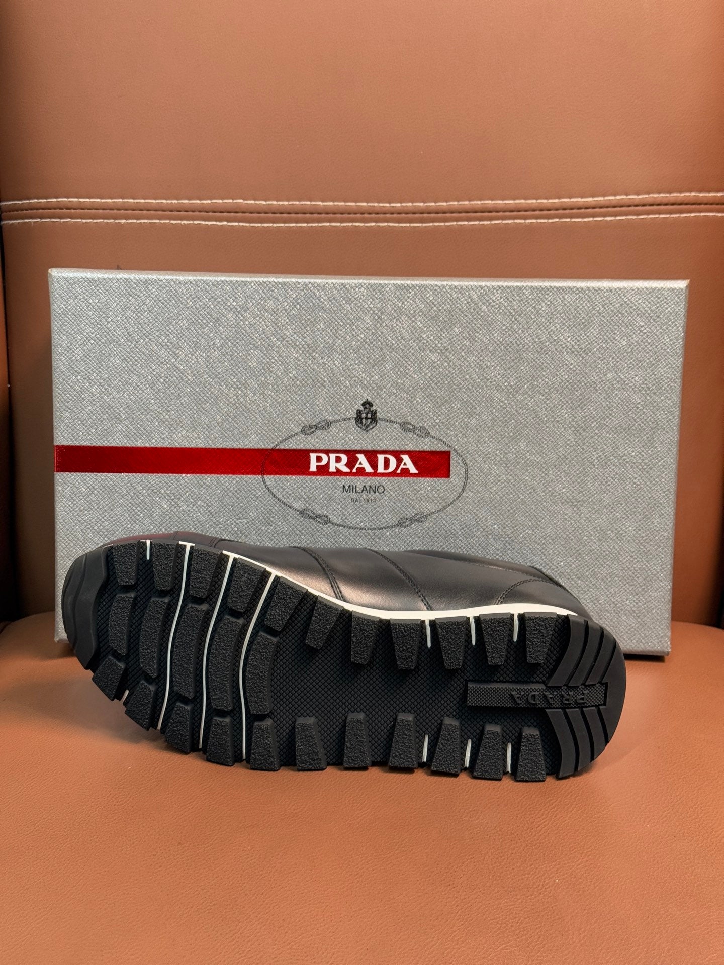 Prada unisex sneaker outsole view with deep tread pattern and dark rubber grip