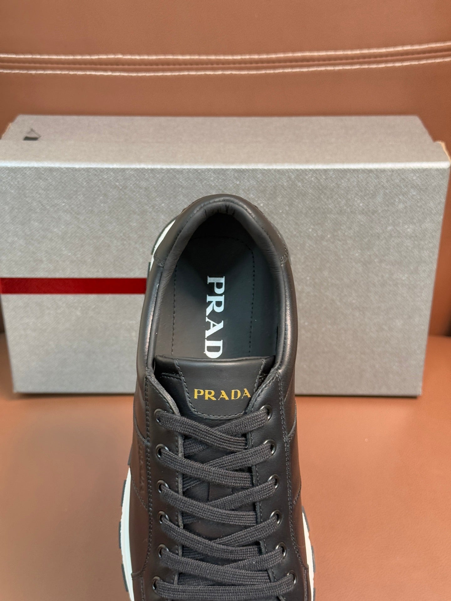 Prada unisex sneaker close-up, dark lace-up upper with tongue logo detail