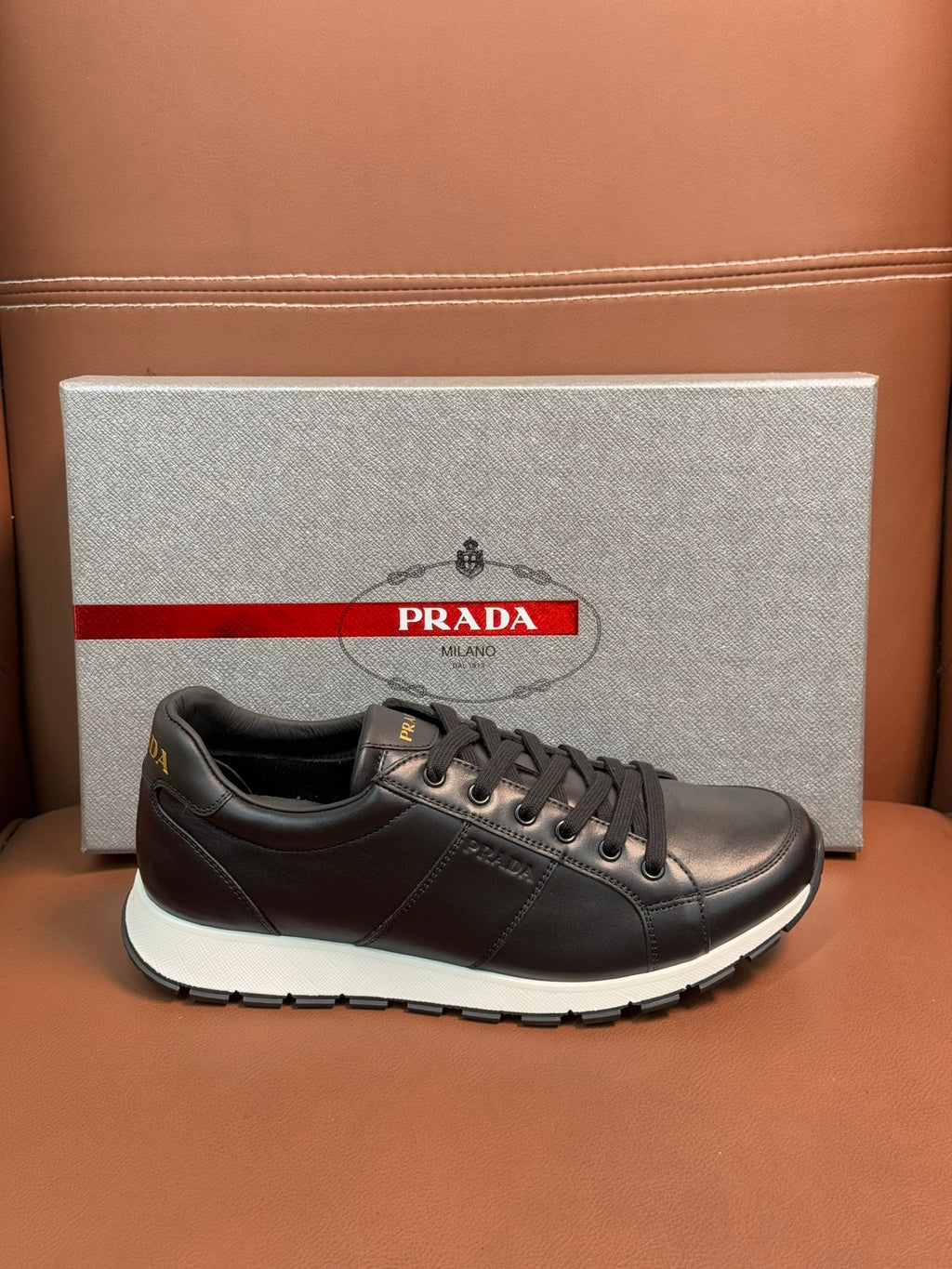 Prada unisex sneakers single shoe side view, dark leather lace-up with white sole edge