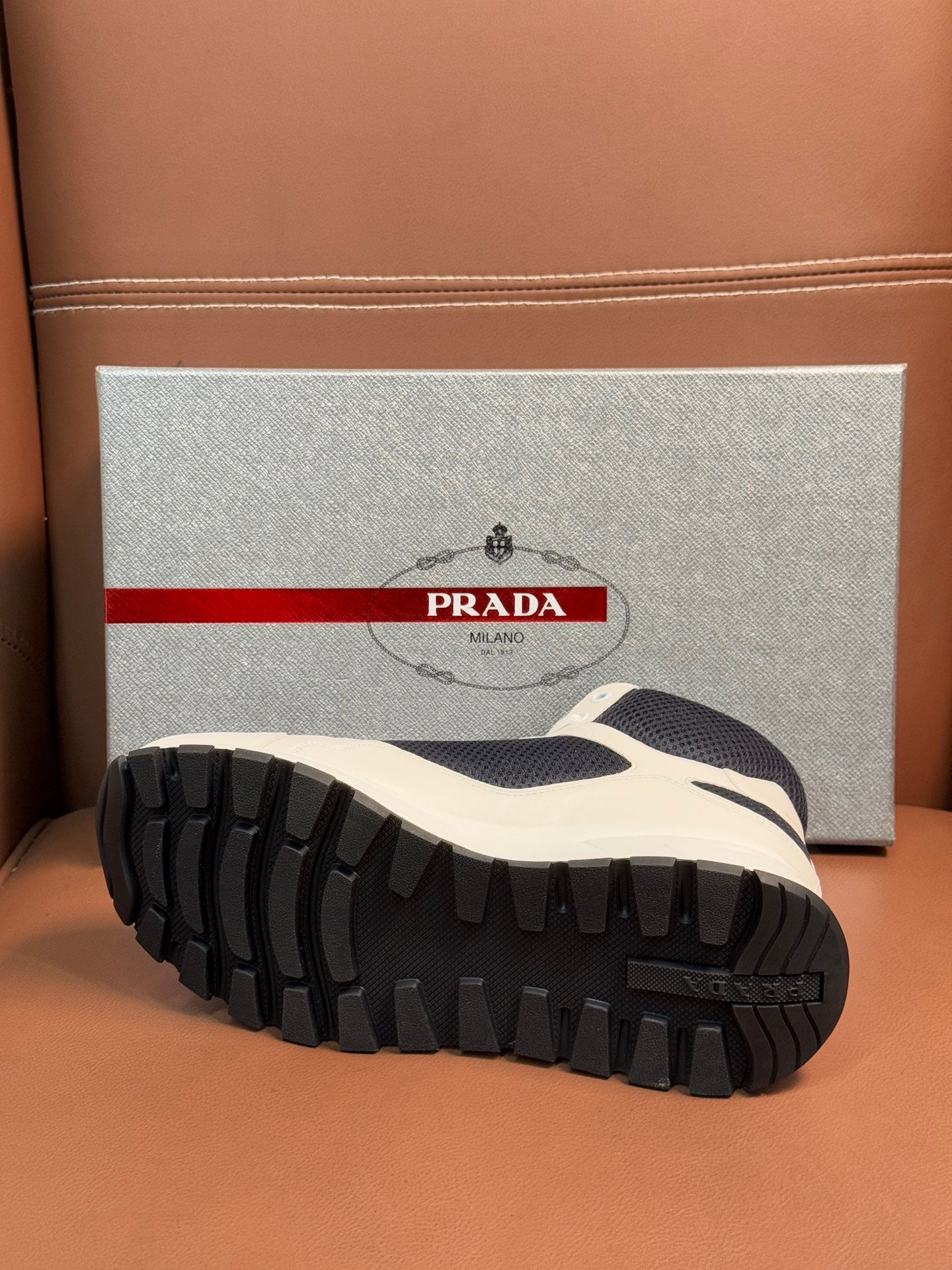 Sole view of lace-up sneakers with deep tread and white/dark navy upper