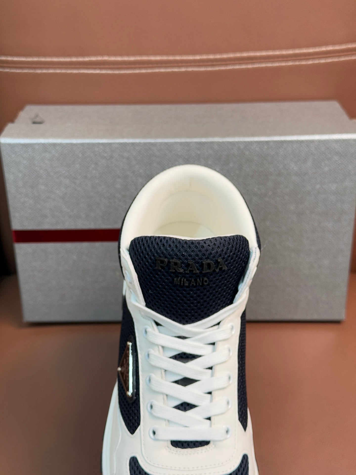 Sneaker upper close-up with white laces, dark navy mesh panel, and stitched logo