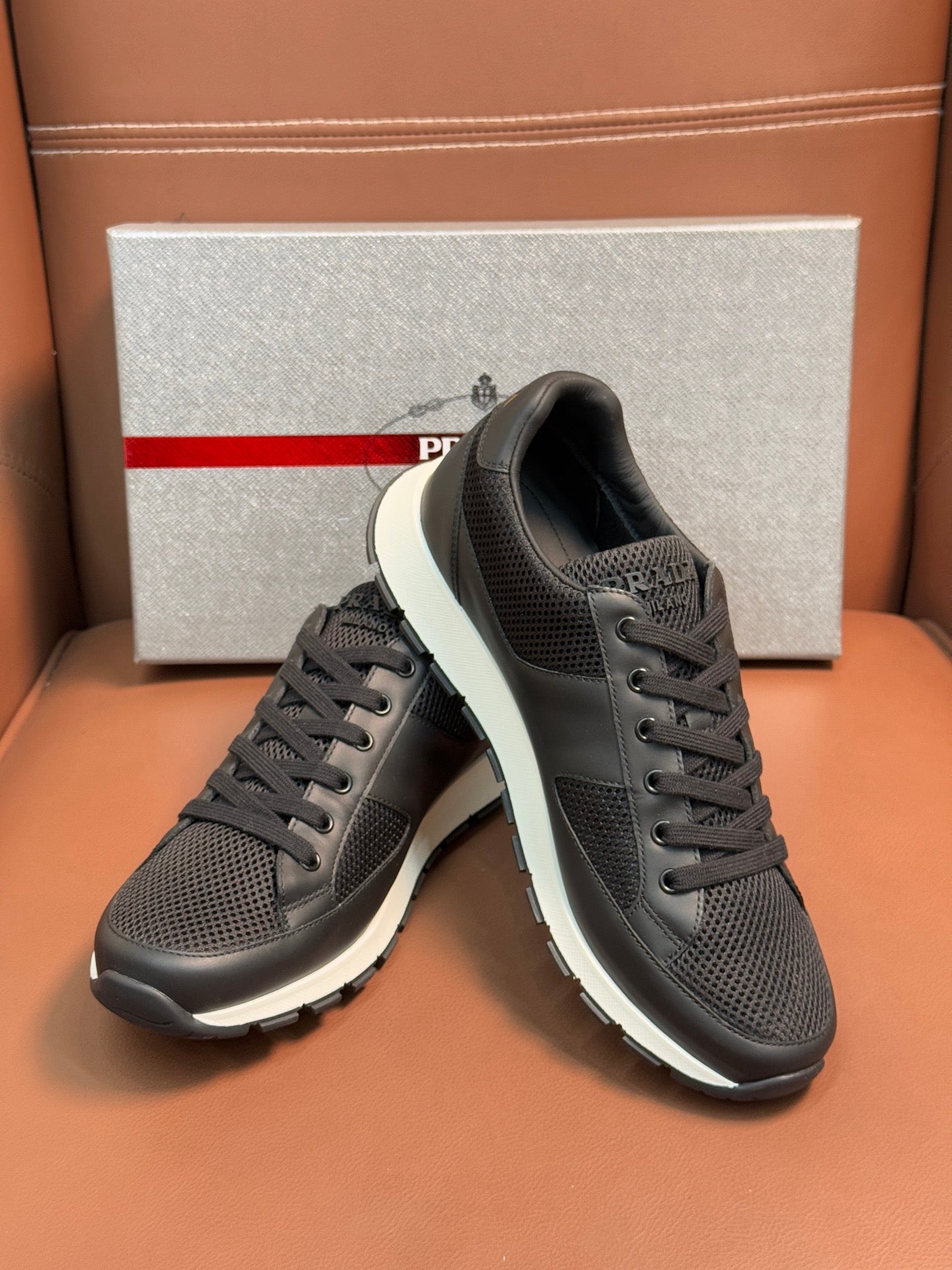Prada unisex low-top sneakers, dark charcoal mesh, white midsole, side by side