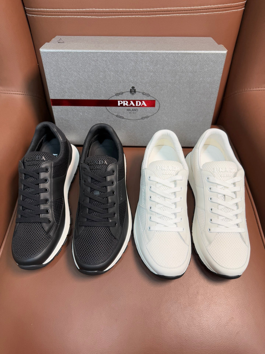 Prada unisex sneaker pair: dark charcoal and white lace-up low-tops