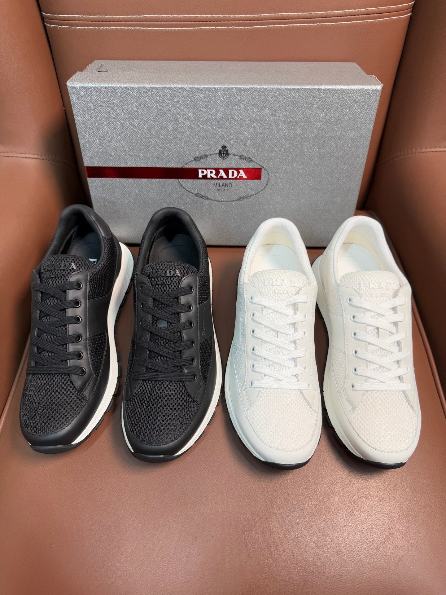 Prada unisex sneaker pair: dark charcoal and white lace-up low-tops