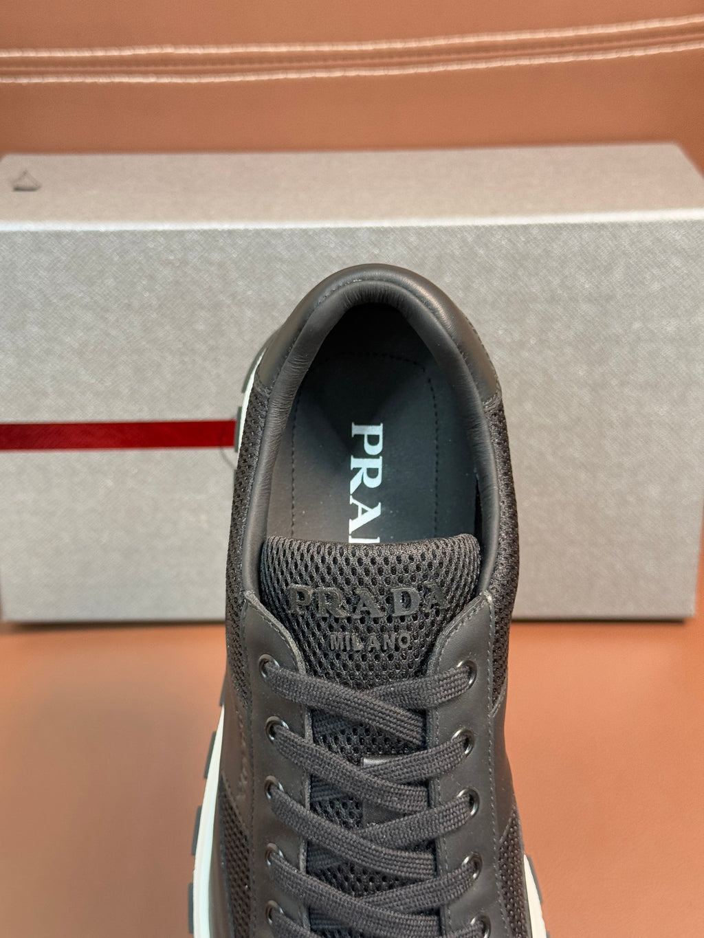 Prada unisex dark charcoal sneaker, close-up front with mesh vamp and laces