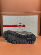 Prada unisex sneaker outsole view, dark rubber tread with brand detail