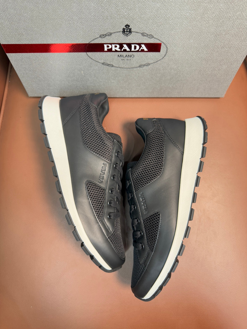 Prada unisex low-top sneakers, dark charcoal mesh, white midsole, angled view