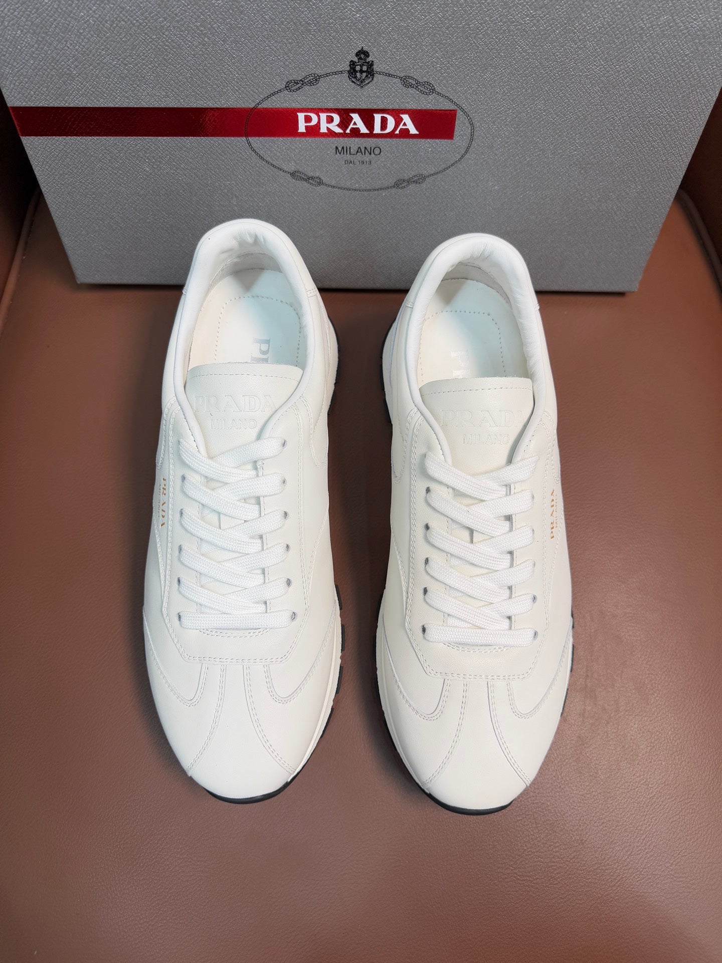 White leather low-top sneakers with white laces and cushioned tongue