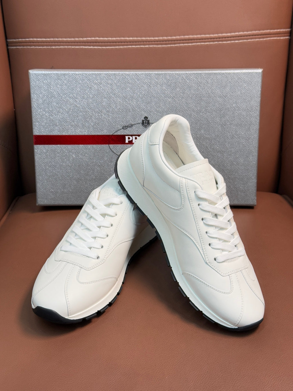 White leather sneakers, angled front view, with white laces and side seam