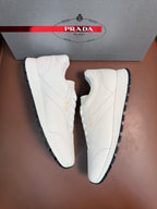 White low-top sneakers displayed as a pair with treaded rubber outsoles