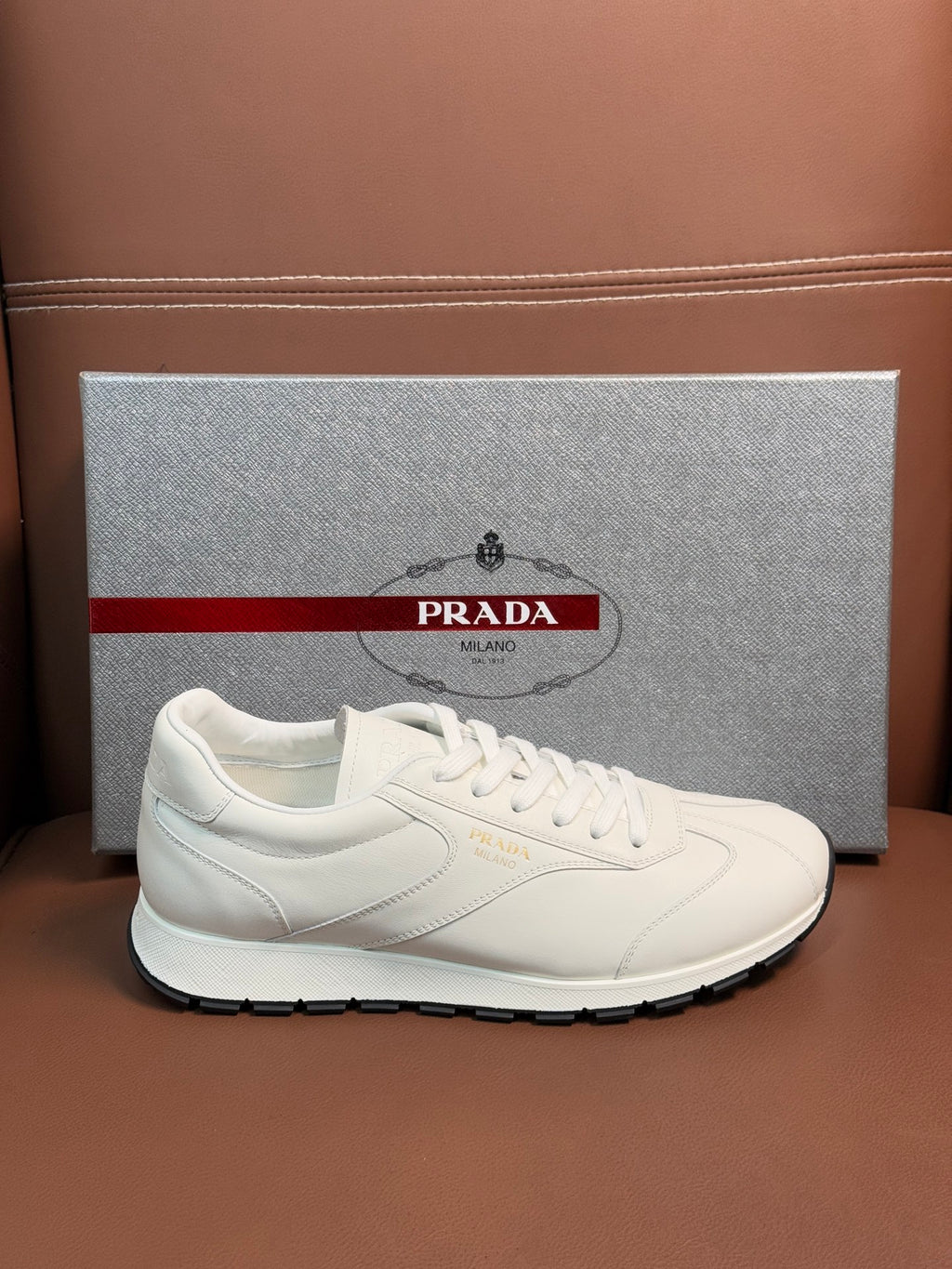 White leather lace-up sneaker with Prada logo on side and rubber sole