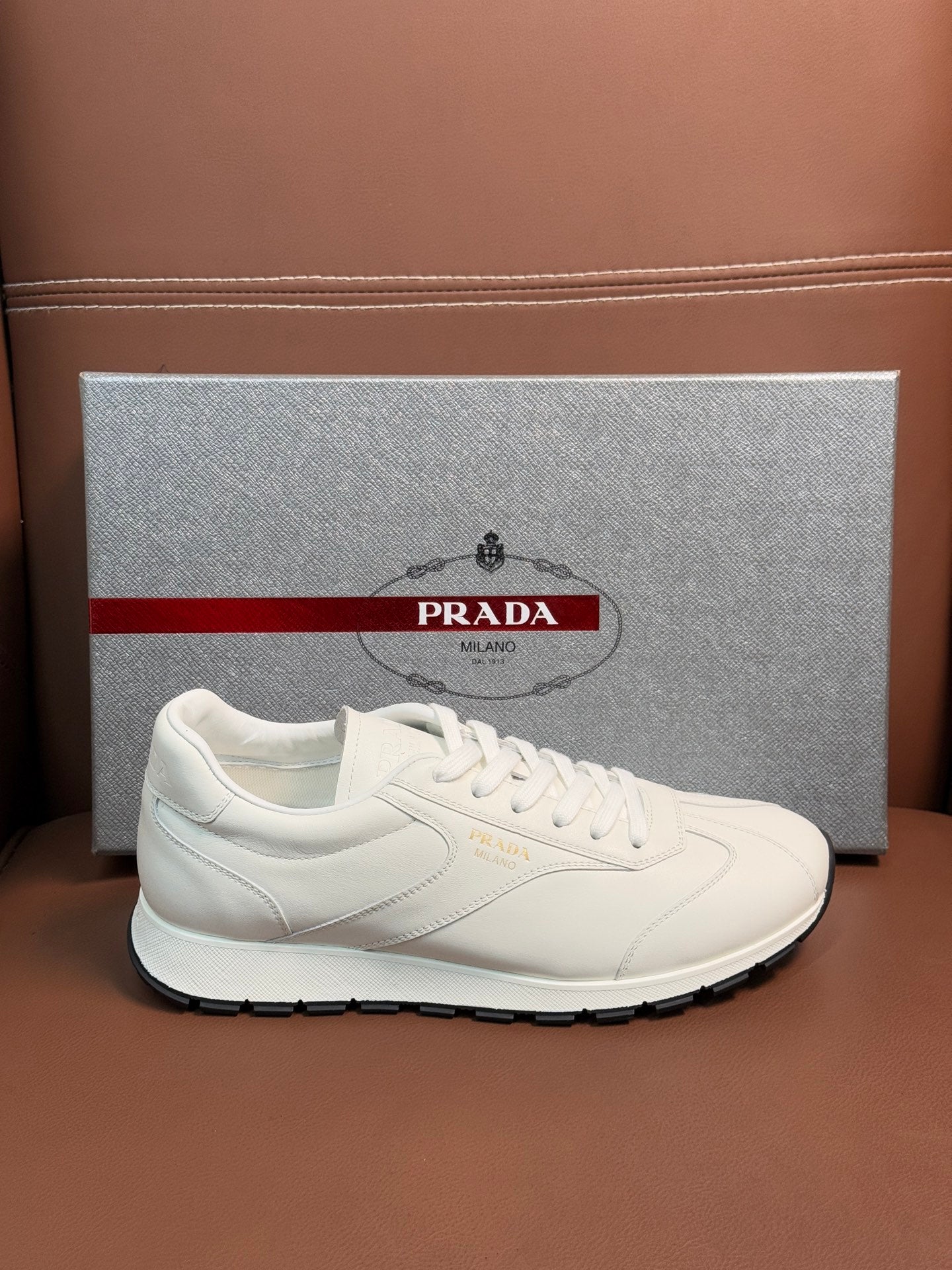 White leather lace-up sneaker with Prada logo on side and rubber sole