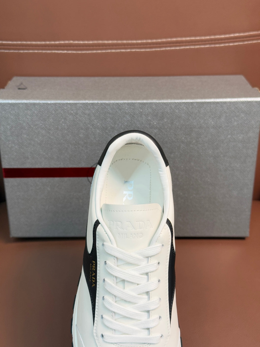 White unisex sneaker toe with lace-up rows and Prada logo on tongue