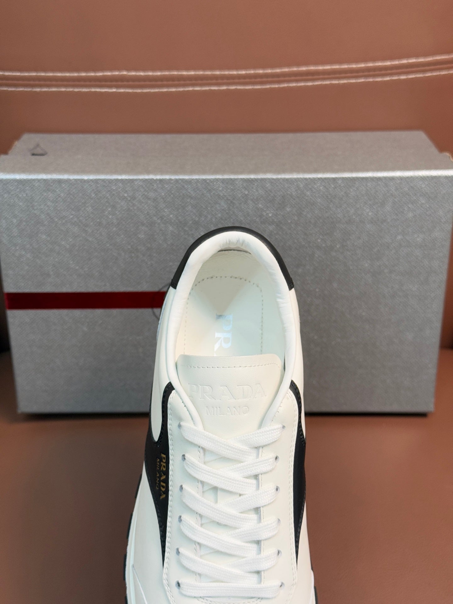 White unisex sneaker toe with lace-up rows and Prada logo on tongue