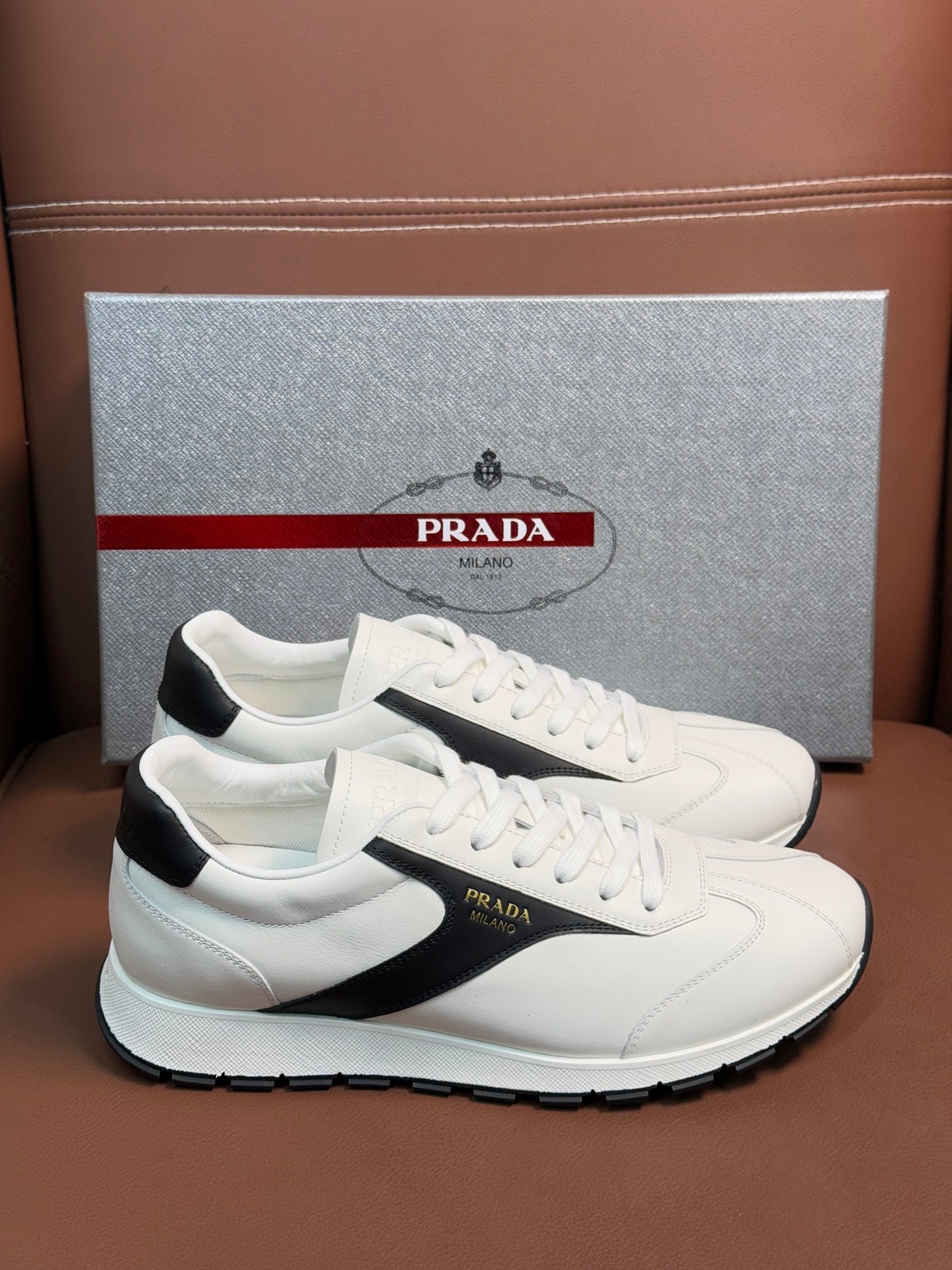White unisex sneakers with black side stripe and Prada logo on tongue