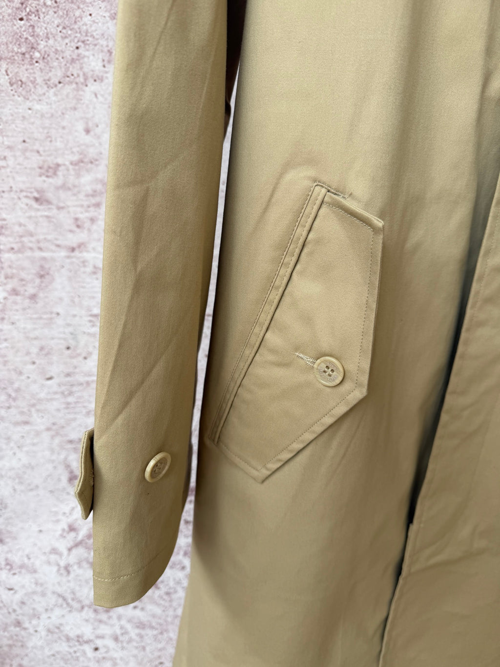 Tan coat sleeve and flap pocket with button detail.