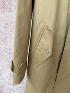 Tan coat sleeve and flap pocket with button detail.
