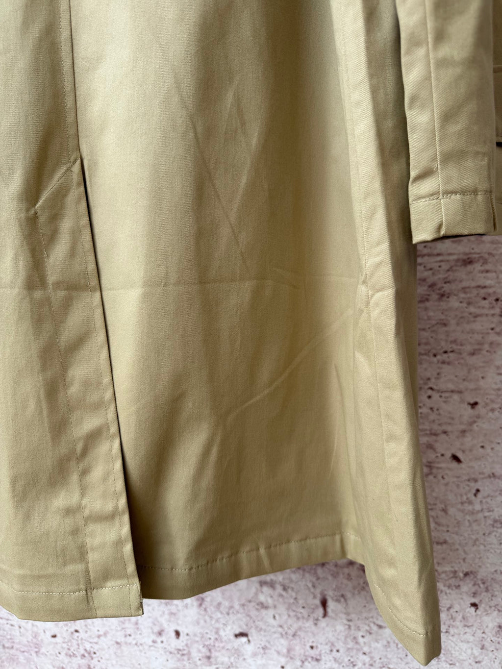 Tan coat back with central seam and side hem slits.