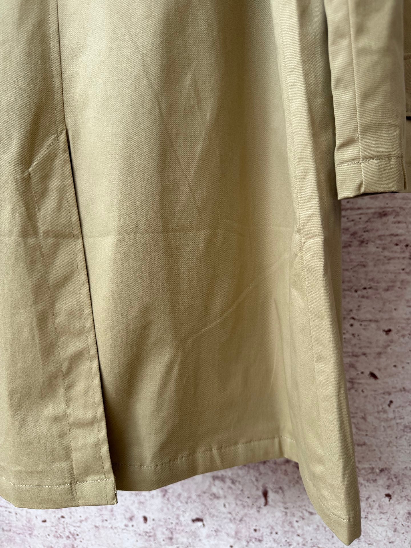 Tan coat back with central seam and side hem slits.