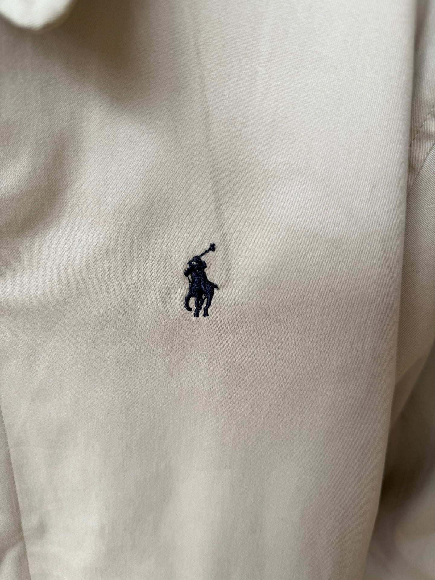 Tan coat with small navy Polo logo embroidered on chest.