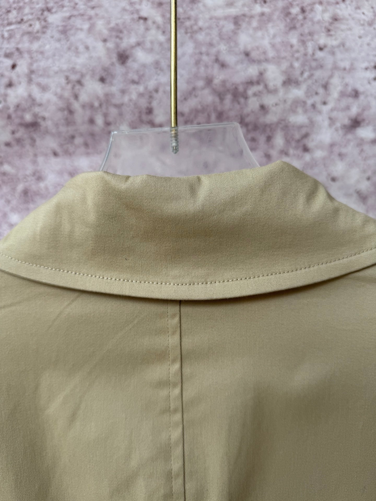 Tan coat back yoke seam and standing collar edge.