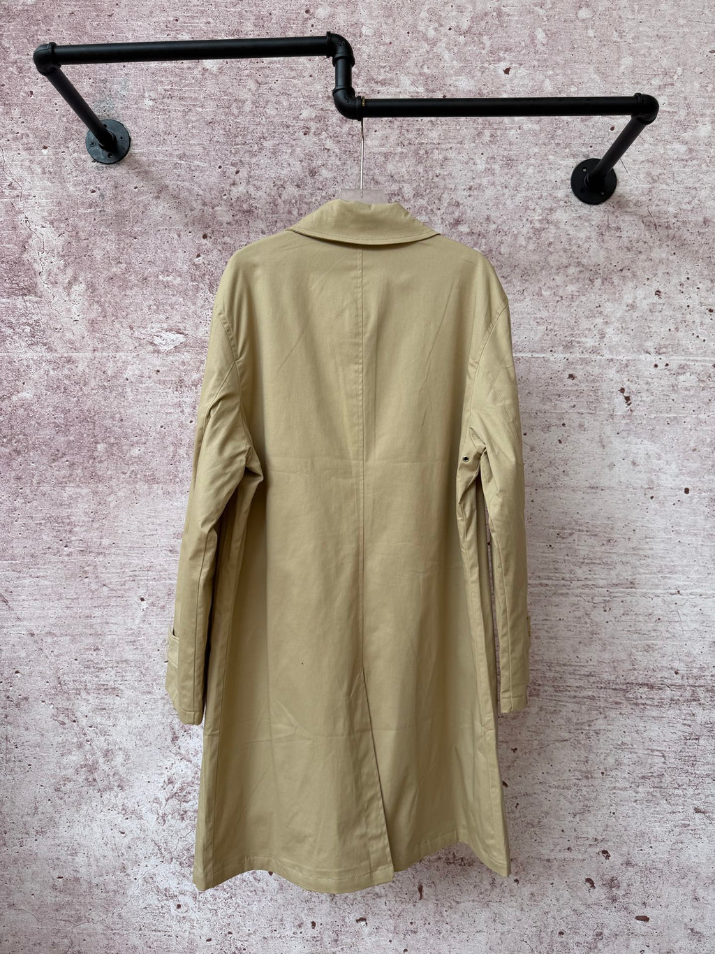 Back of tan long coat with yoke seam and central back panel.