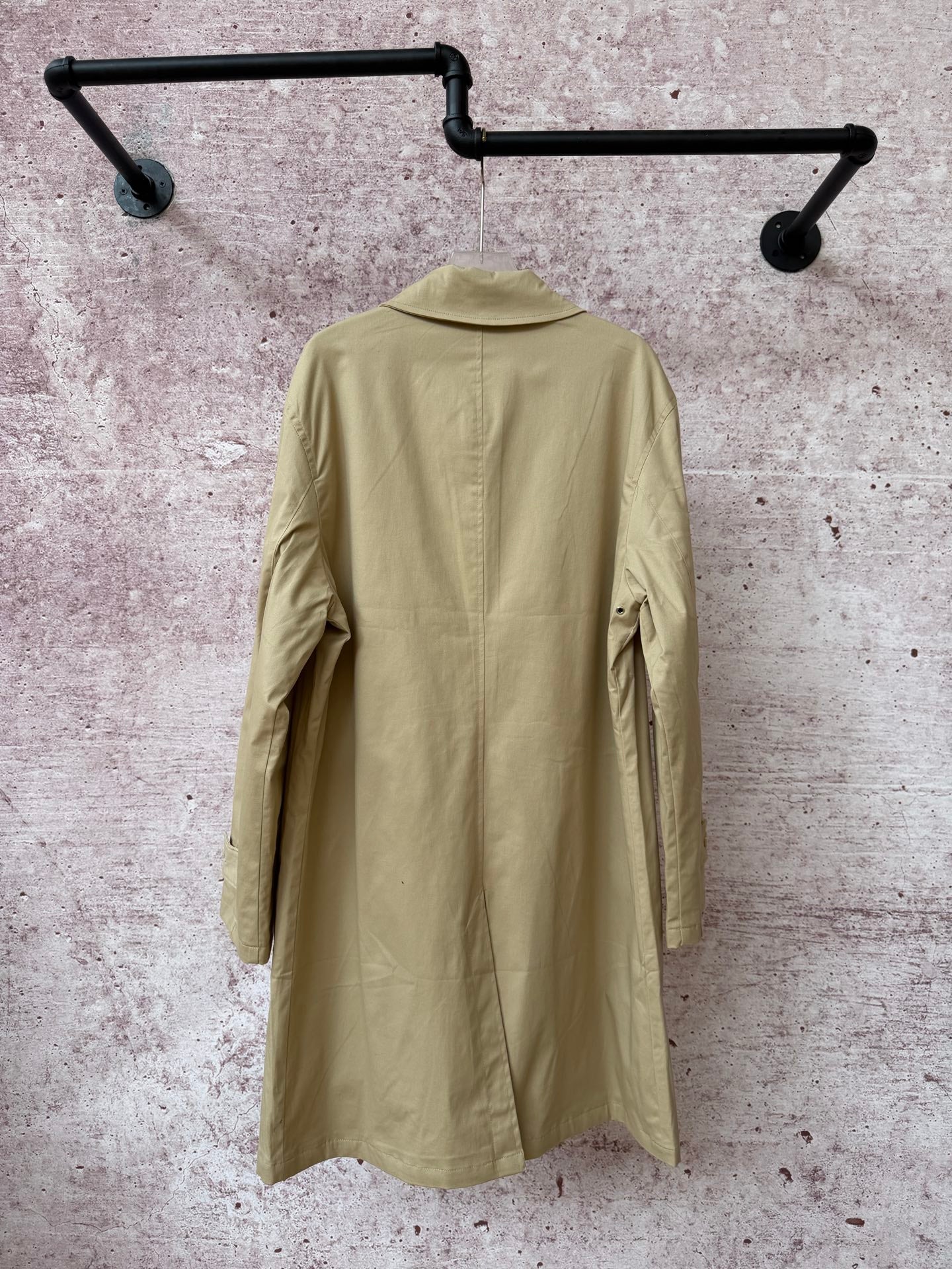 Back of tan long coat with yoke seam and central back panel.