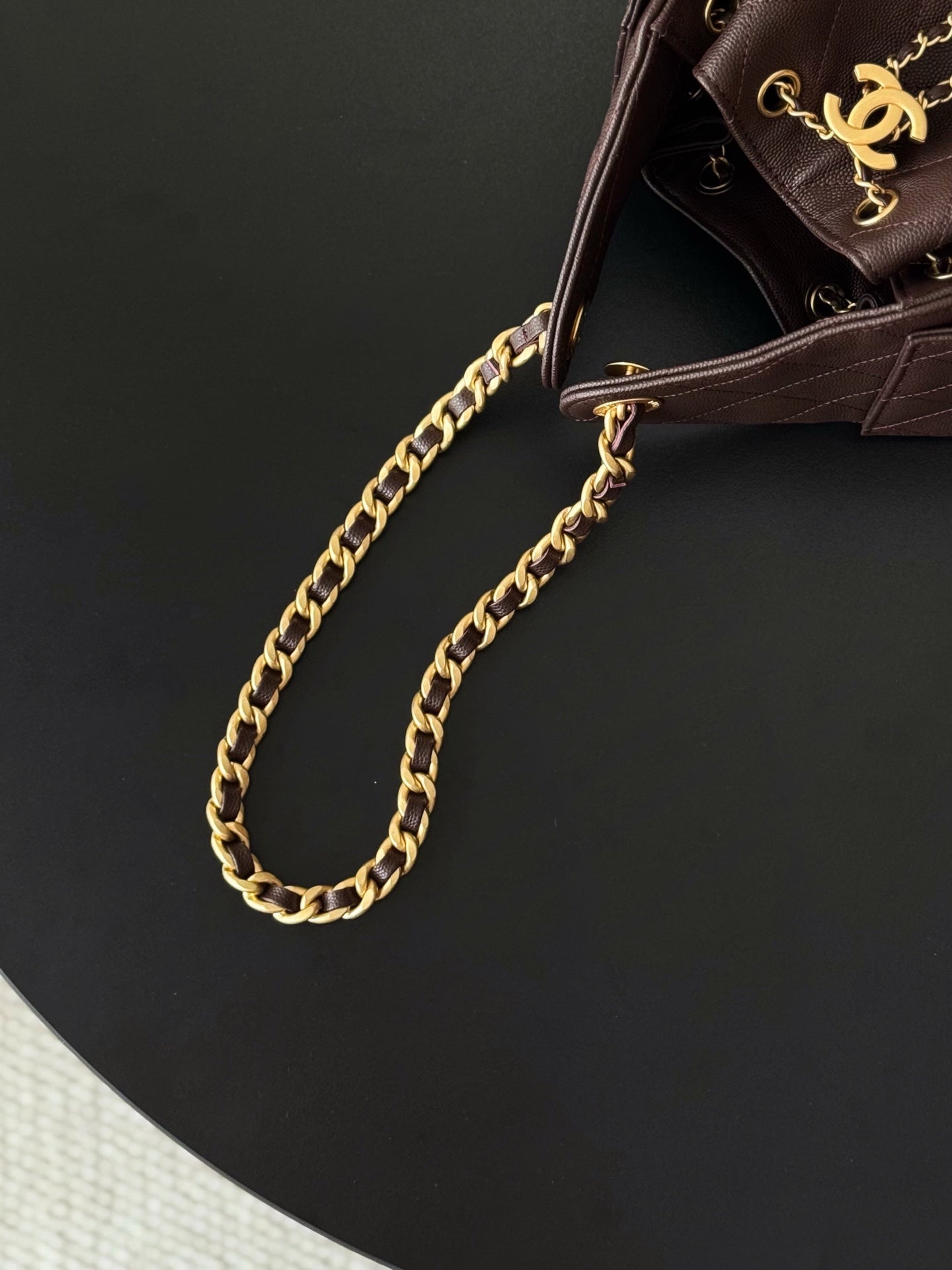 Chanel bag side view with gold chain strap and dark plum leather corner hardware