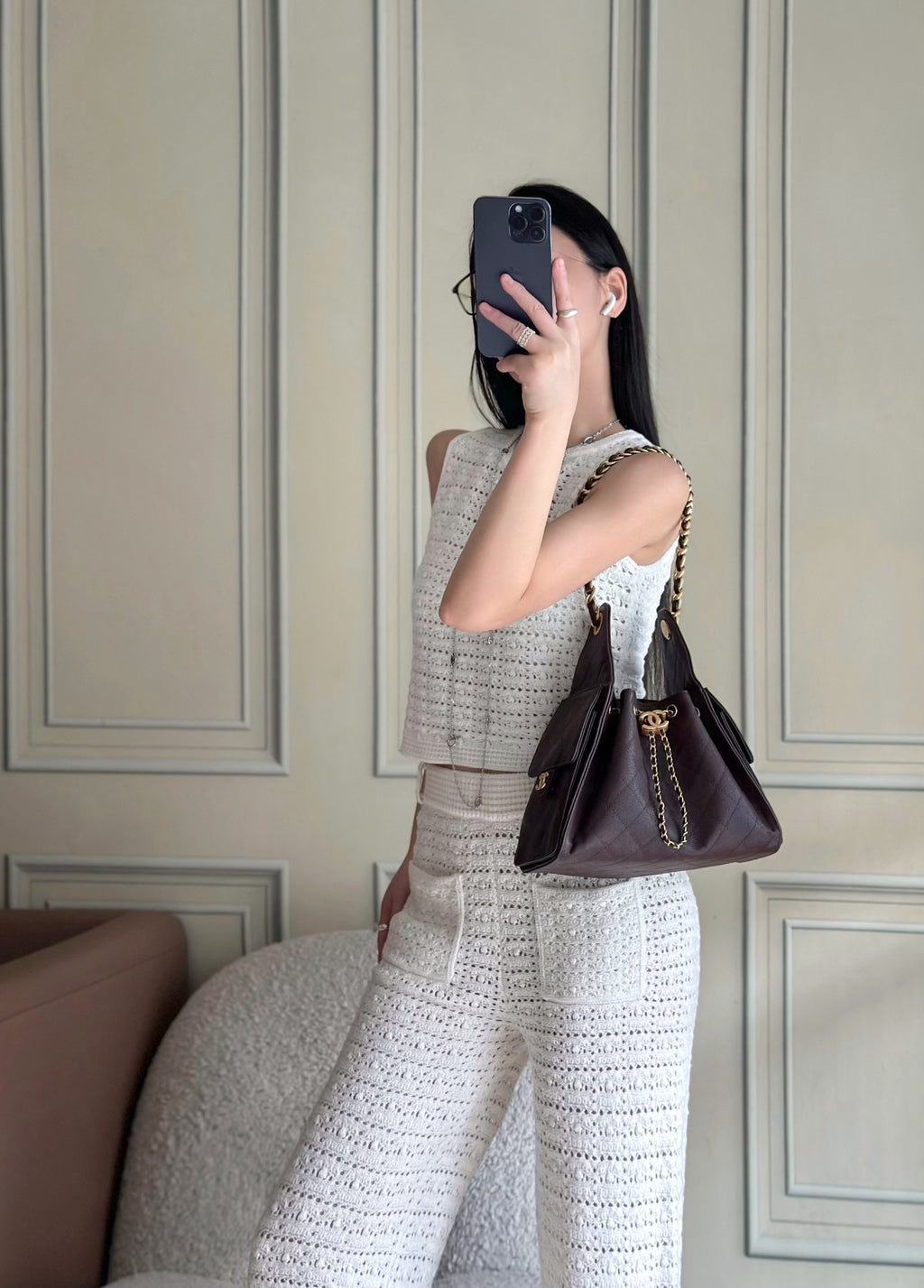 Chanel bag in dark plum with gold chain strap, held on model with top flap closure