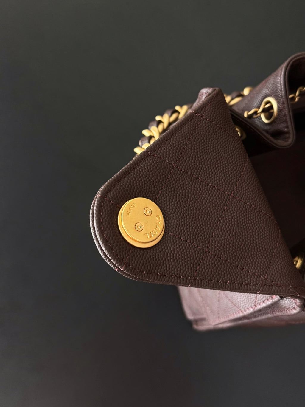Chanel bag side pocket with gold button detail on dark plum quilted leather