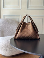 Brown quilted triangle shoulder bag with top handle, chain strap, and logo clasp