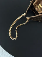 Gold-tone chain shoulder strap on a brown quilted flap bag