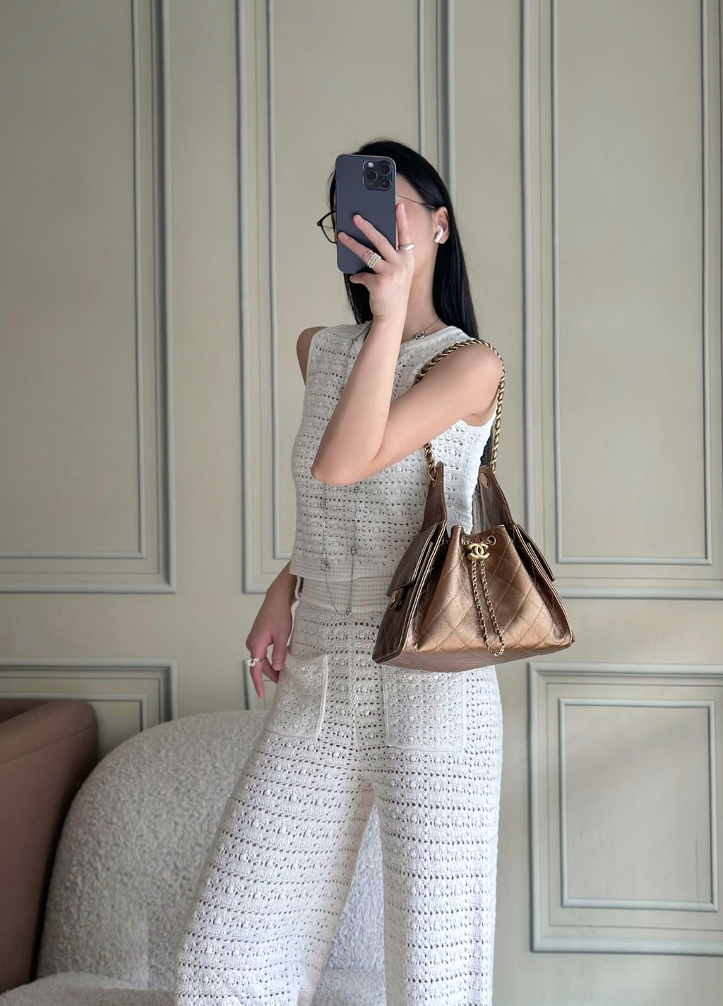 Brown quilted triangle shoulder bag worn on shoulder with chain strap