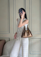 Brown quilted triangle shoulder bag worn on shoulder with chain strap