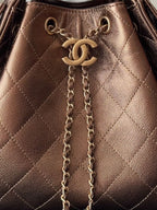 Brown quilted bag detail with Chanel logo, hanging chain strap, and gold hardware