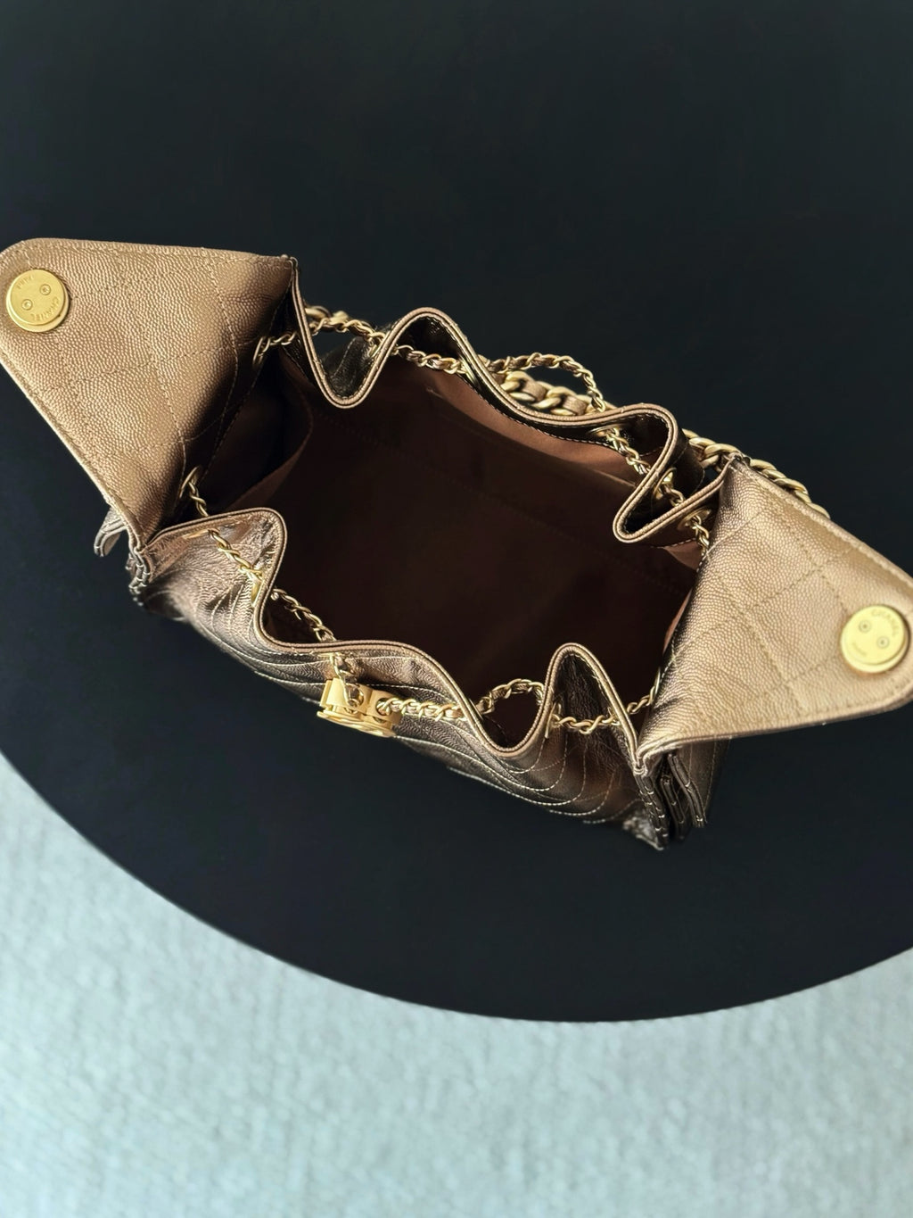 Brown quilted triangle bag open view with chain strap and gold-tone snap buttons