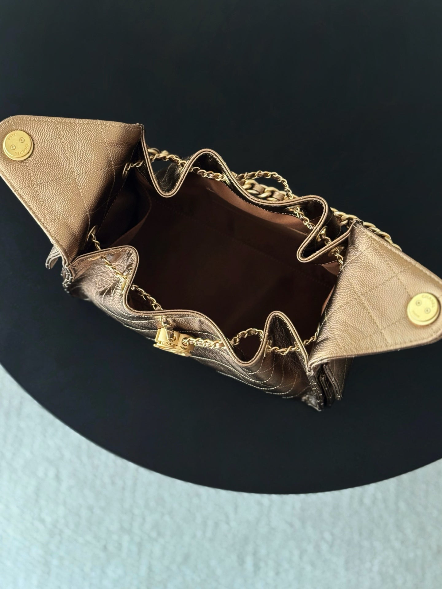 Brown quilted triangle bag open view with chain strap and gold-tone snap buttons
