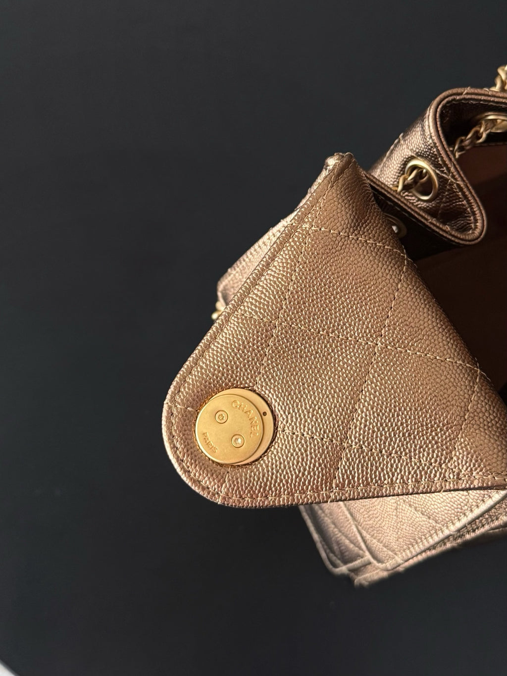 Brown triangle bag corner with round snap button and gold-tone logo hardware