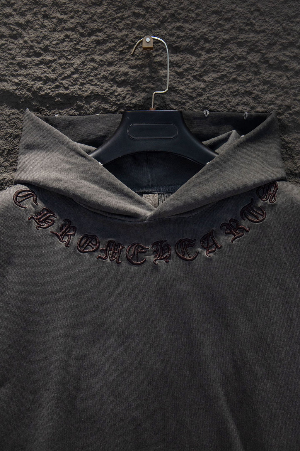 Dark gray hoodie sleeve with embroidered symbols and script detail