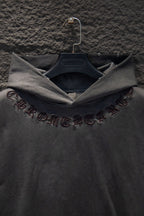 Dark gray hoodie sleeve with embroidered symbols and script detail
