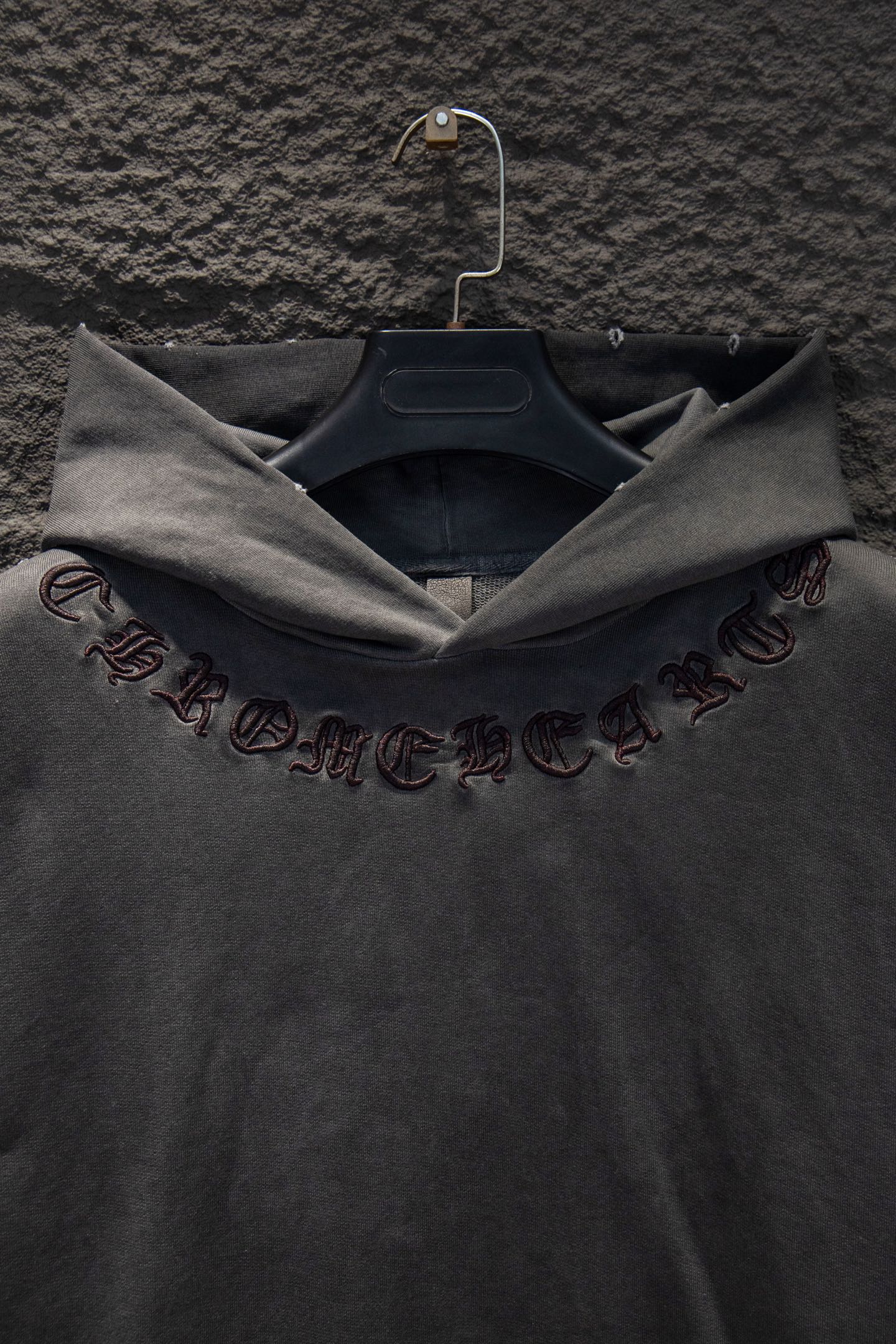 Dark gray hoodie sleeve with embroidered symbols and script detail