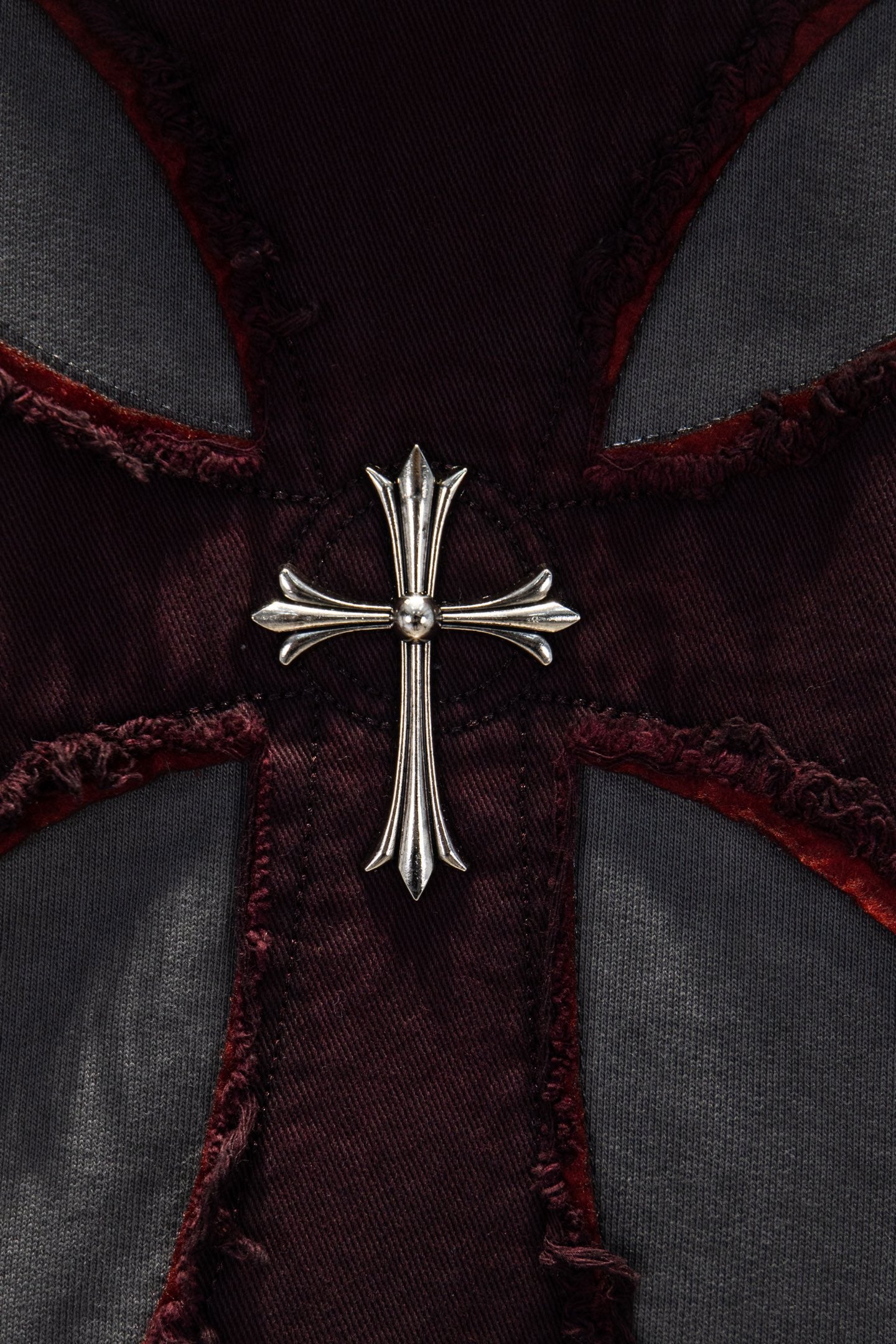 Embroidered cross pendant detail on maroon-and-gray hoodie front