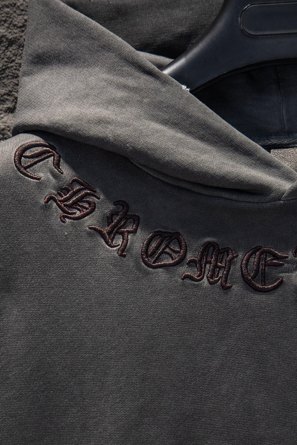 Embroidered text and symbols on dark gray hoodie sleeve cuff
