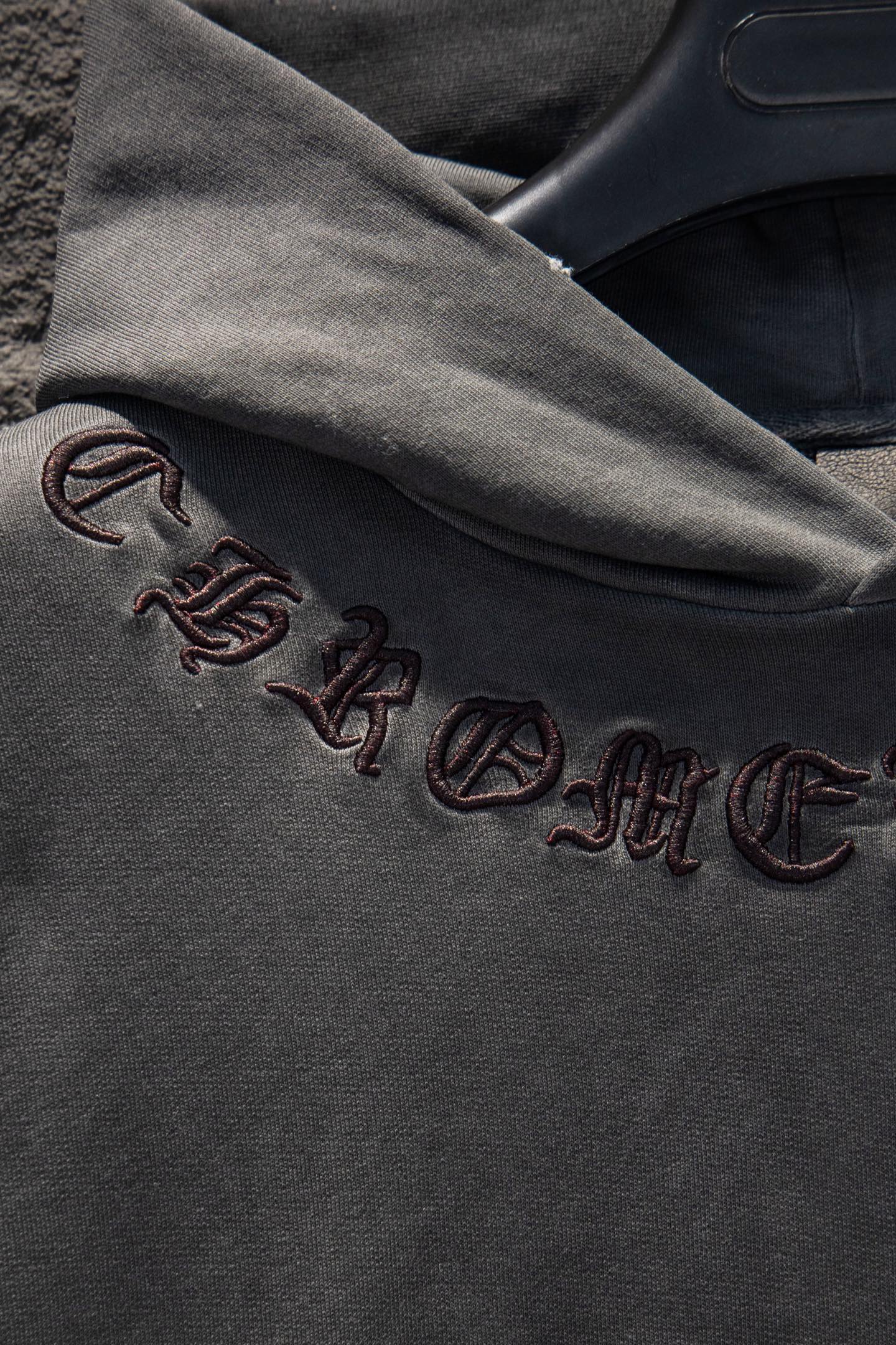 Embroidered text and symbols on dark gray hoodie sleeve cuff
