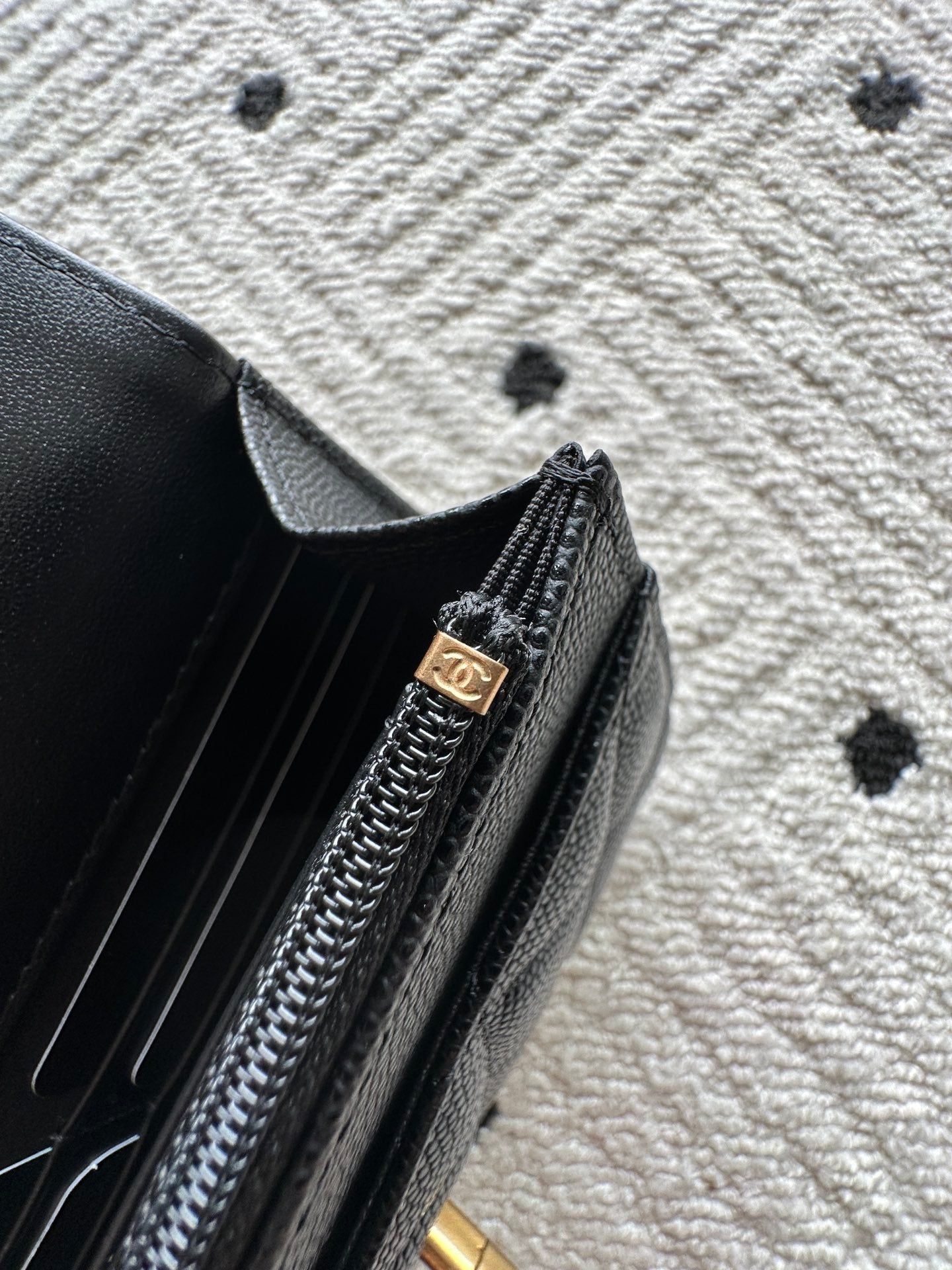 Black bag zipper detail with gold-tone pull and Chanel logo charm