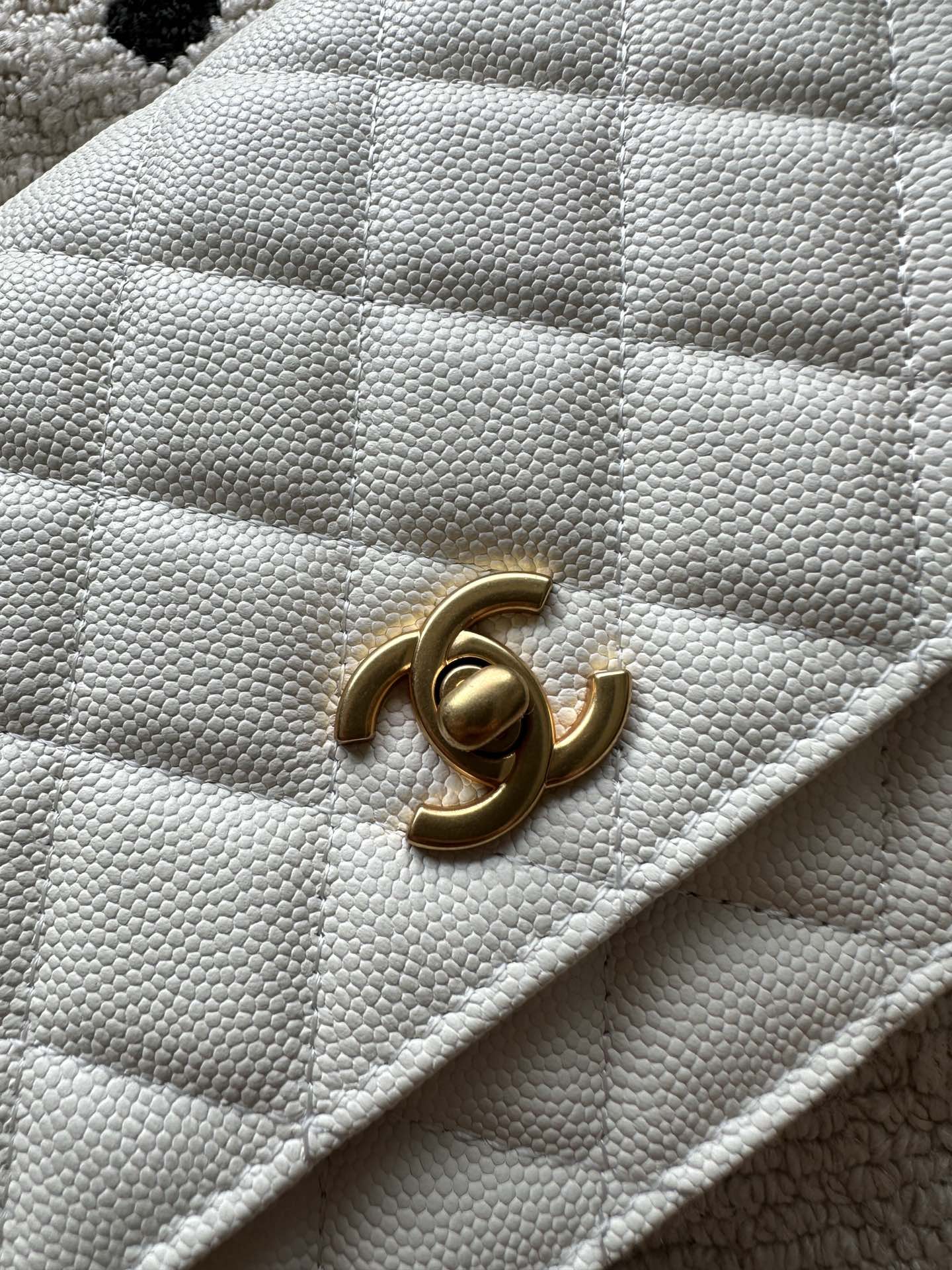 Chanel white quilted bag close-up of gold CC turn-lock on flap