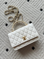 Chanel quilted white bag with gold CC logo and chain strap, flap front view