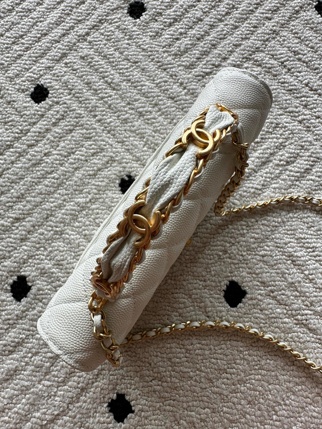 Chanel white quilted bag showing chain links and gold metal hardware, side view