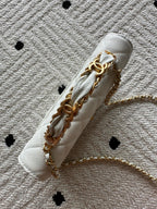 Chanel white quilted bag showing chain links and gold metal hardware, side view